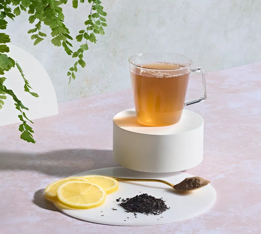 Infuso a base di erbe Herbalife in tazza di vetro con limone e foglie di tè
